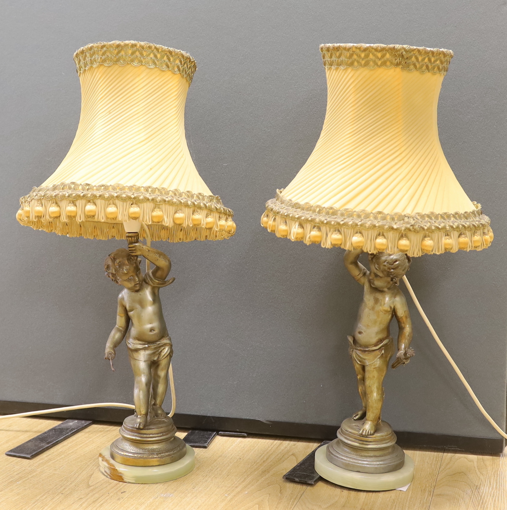 A pair of early 20th century spelter ‘cherub’ table lamps with shades, 63cm total